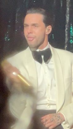 a man in a white tuxedo holding a bottle