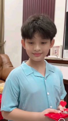 a young boy holding a red heart shaped box