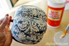 a person holding a hat on top of a wooden table next to paint and glue