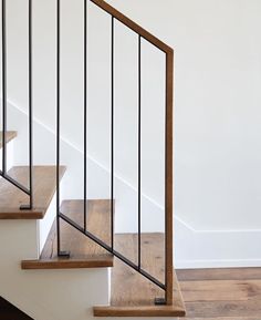 a wooden and metal stair rail in a white room