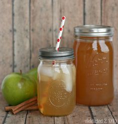 two mason jars filled with apple pie moonsshine sitting on top of a wooden table