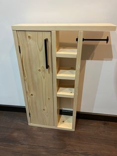 a wooden cabinet sitting on top of a hard wood floor next to a white wall