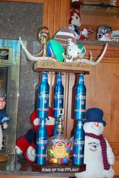 two snowmen are standing next to some bottles and an iceman is sitting on the shelf