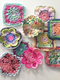 several crocheted squares are arranged on a white surface, each with a flower in the center