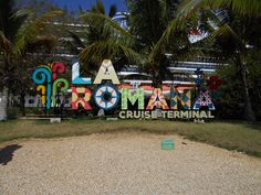 a sign that says la romana cruise terminal in front of some trees and bushes