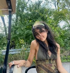 a woman in a dress is standing next to a golf cart and holding the driver's arm