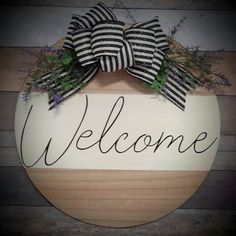 a welcome sign hanging on the side of a wooden wall with two large black and white striped bows