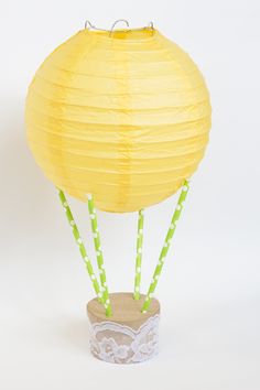 a yellow paper lantern in a vase with green straws