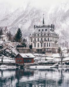 a large building sitting on top of a snow covered hill next to a body of water