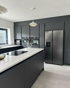 a modern kitchen with stainless steel appliances and white counter tops, along with an island in the middle