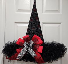 a black and red christmas tree wreath hanging on a door handle with ribbon around it