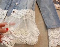 a woman's hand holding onto a piece of white lacy material with lace on it