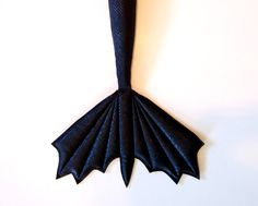 an origami mermaid tail hanging on the wall in front of a white wall