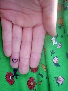 a person's hand with a heart tattoo on it