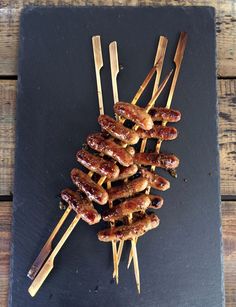 several skewered sausages are on a slate platter with toothpicks