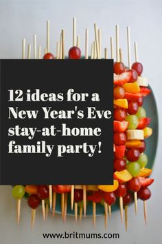 a plate filled with lots of fruit on top of skewers next to a sign that says, 12 ideas for a new year's eve stay at home family party