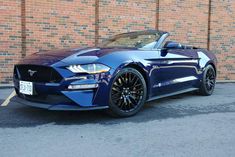 a blue sports car parked in front of a brick building with black rims and chrome wheels