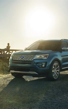 a blue suv parked on the side of a dirt road next to a wooden bridge