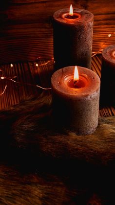 three lit candles sitting on top of a wooden table