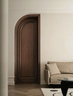 a living room with a white couch and wooden door in the corner next to a coffee table