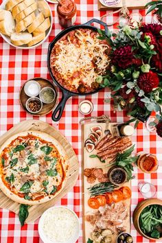 a table topped with pizzas and other foods on top of a checkered table cloth