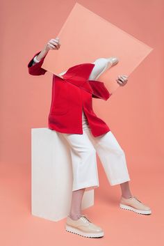 a woman in red jacket and white pants holding up a piece of paper