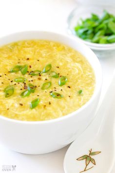 there is a bowl of soup with green onions in it and another bowl next to it