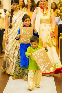 two young boys holding up signs while standing next to each other in front of people