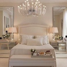 a white bed sitting in a bedroom next to a chandelier