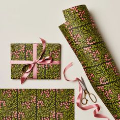 wrapping paper with pink flowers and green leaves on it next to a pair of scissors