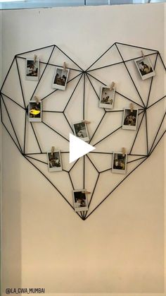 a heart shaped wall hanging on the side of a white wall with multiple photos attached to it