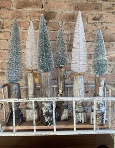 four glass trees are sitting on top of a shelf in front of a brick wall