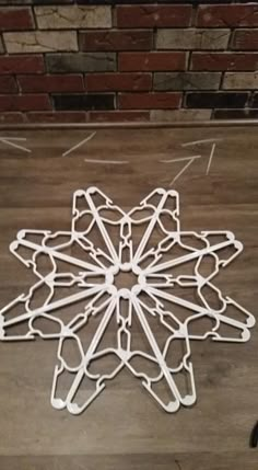 a white snowflake sitting on top of a wooden floor next to a brick wall