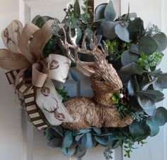 a wreath with deer and greenery on the front door