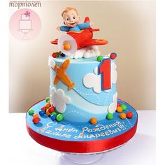 a birthday cake for a one year old boy with an airplane and clouds on it