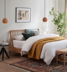 a bed sitting in a bedroom next to a table with a plant on top of it