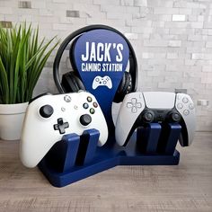 two video game controllers and a jack's gaming station stand with headphones on it