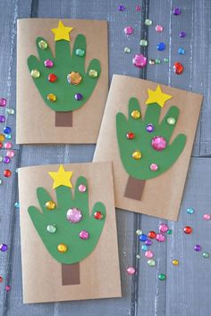 three handprinted christmas trees on brown paper with confetti scattered around them