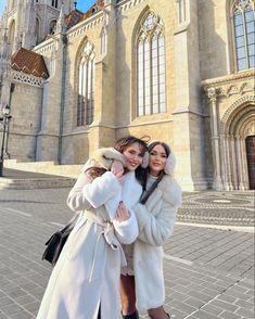 two women standing in front of a large building