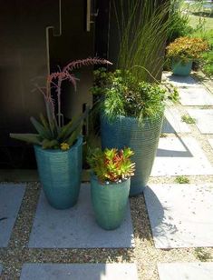 three large blue planters sitting next to each other on top of a stone walkway