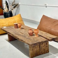 a wooden table with two vases sitting on top of it next to a brown pillow