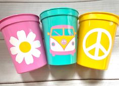 three colorful trash cans with peace signs and a vw bus painted on the side