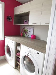 a washer and dryer in a small room with pink paint on the walls