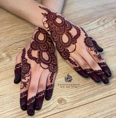 two hands with henna tattoos on them sitting on a wooden floor next to each other