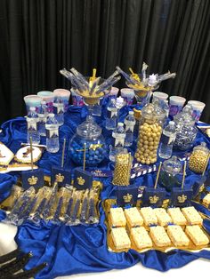 a blue table topped with lots of desserts and candy bar items next to a black curtain