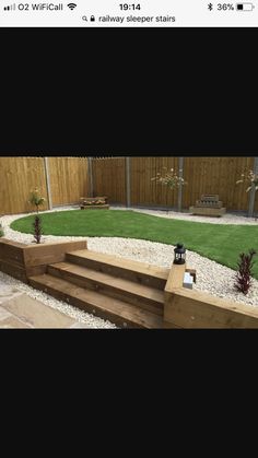 a backyard with artificial grass and wooden steps leading up to the back yard, surrounded by gravel