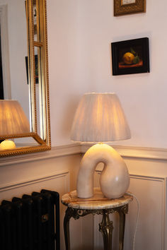 a lamp sitting on top of a table next to a mirror and radiator