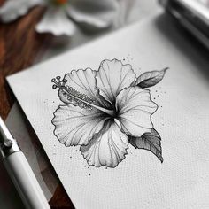 a drawing of a flower on paper next to a pen and ink roller with flowers in the background