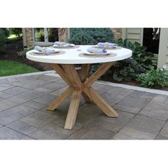 a white table with plates on it sitting in the middle of a brick patio area