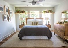 a bed sitting in a bedroom next to a window with lots of plants on top of it